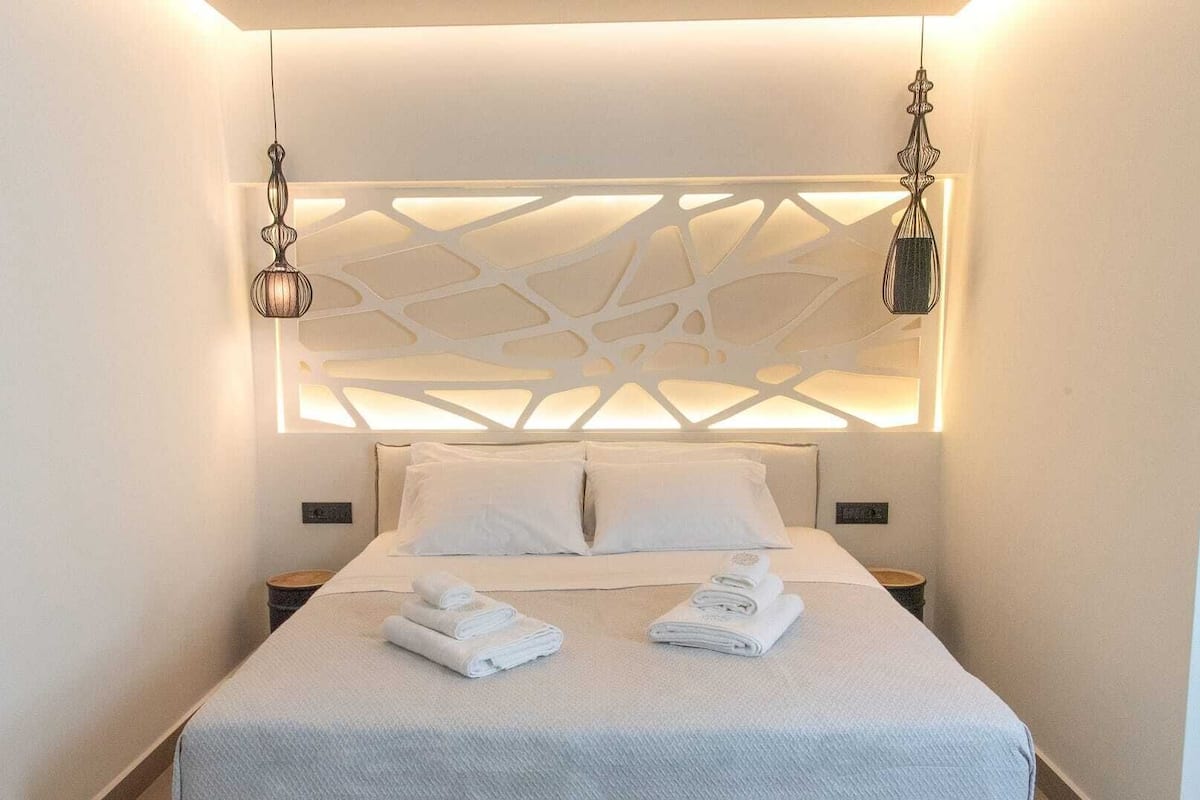 A modern hotel room with a geometric wall design, a neatly made bed with white linens, and two bedside tables.