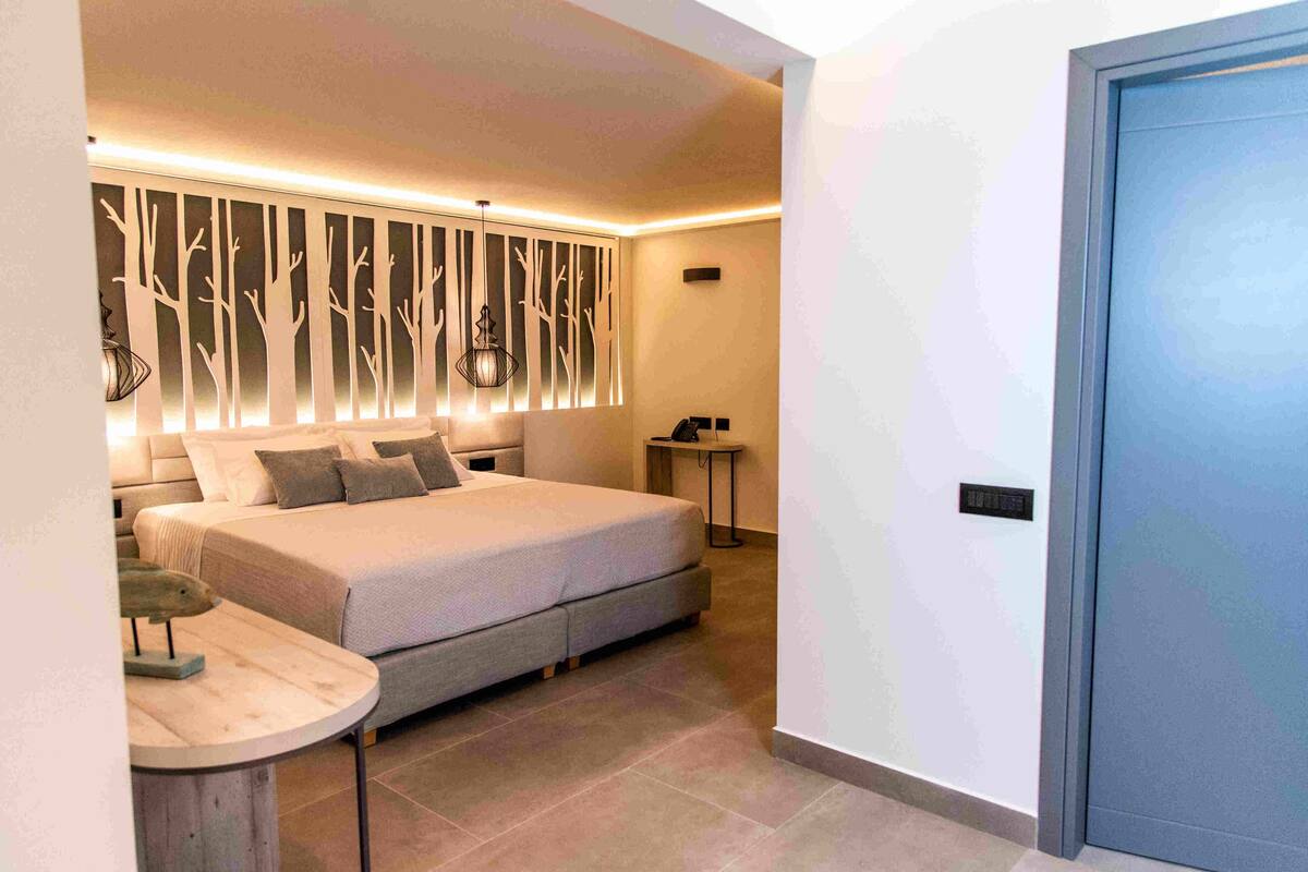 A modern bedroom with a large bed, a bedside table, and a wall-mounted light fixture.