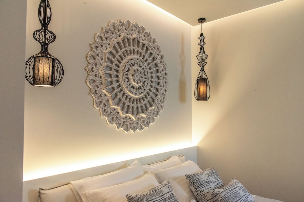 A bedroom with a bed, decorative wall art, and two wall-mounted lamps.