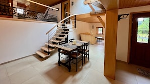 A modern interior with a wooden staircase, a dining area, and a view of the outdoors. - Quiet Vosges Cottage for 4 with Terrace and Children's Area (Le Saulcy)
