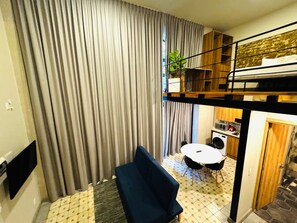 A compact hotel room with a bunk bed, a small dining area with a table and chairs, a washing machine, and a large window with curtains. - Elegante loft urbano (Guadalajara)