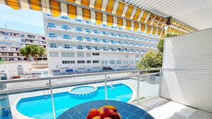 Ein Balkon mit Pool, einer Obstschale und Blick auf ein Hotelgebäude.