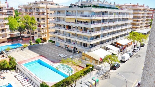 A multi-story hotel with a swimming pool, balconies, and a parking area. - Family apartment in Salou, terrace and pool near the beach (Salou)
