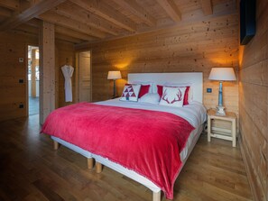 Un dormitorio con paneles de madera, una cama, dos mesitas de noche y una mesilla.