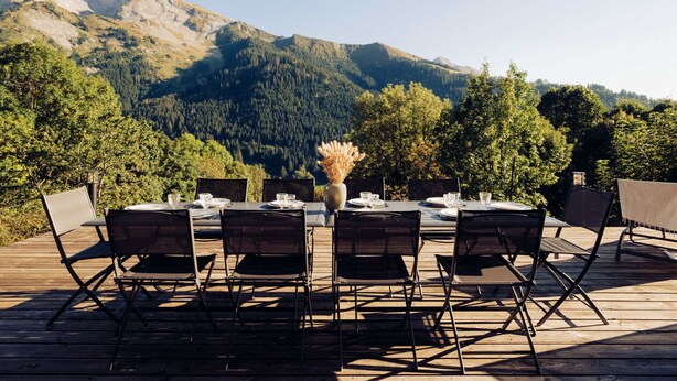 A wooden deck with a table set for six, overlooking a mountainous landscape. - 4★ Chalet, 12 pers, spa, panoramic view, near shuttle (La Clusaz)