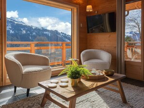 A cozy room with two chairs, a table with a plant, and a TV on the wall. - 4★ Chalet, 12 pers, spa, panoramic view, near shuttle (La Clusaz)