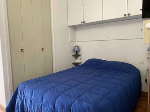 Makuuhuoneessa on sänky, vaatekaappi ja yöpöytä, jossa on lamppu.