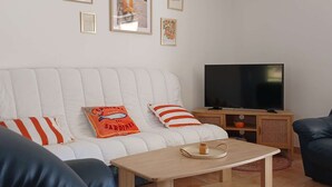 A living room with a white sofa, a television, and a small wooden table.