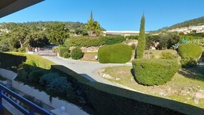 A landscaped garden with neatly trimmed hedges, a winding road, and a distant view of buildings.