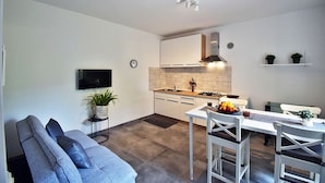 Une cuisine moderne avec des meubles blancs, une cuisinière encastrée et un coin repas comprenant une table et des chaises.