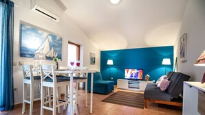 Ein Wohnzimmer mit Essbereich, einer Couch, einem Fernseher und einem Gemälde von Segelbooten.
