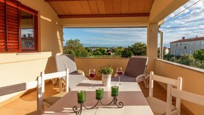 Ein überdachter Balkon mit Tisch und Stühlen für zwei Personen sowie einem Blumentopf.