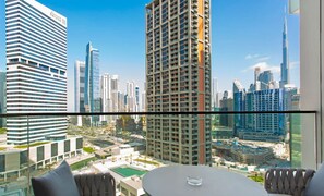 A high-rise hotel room with a city view, a round table, and a sofa.