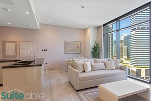 Una sala de estar moderna con un sofá, una mesita de centro y vistas a un paisaje urbano a través de ventanas amplias.