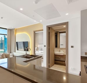 Een moderne hotelkamer met een keukenhoek, een badkamer en een zithoek met uitzicht over de stad.