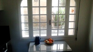 A room with a white table, a bowl of fruit, and a blue mug.