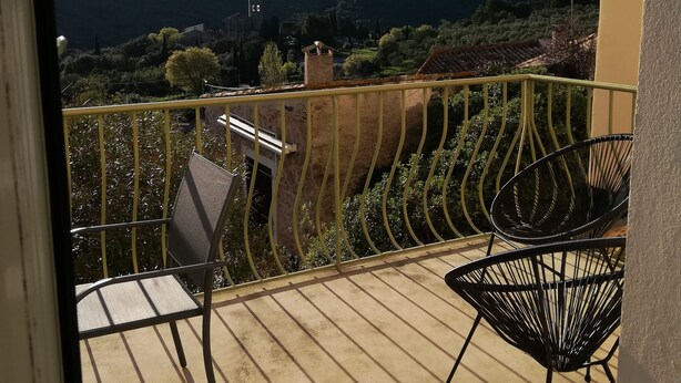 A balcony with a view of a mountainous landscape, a chair, and a table.