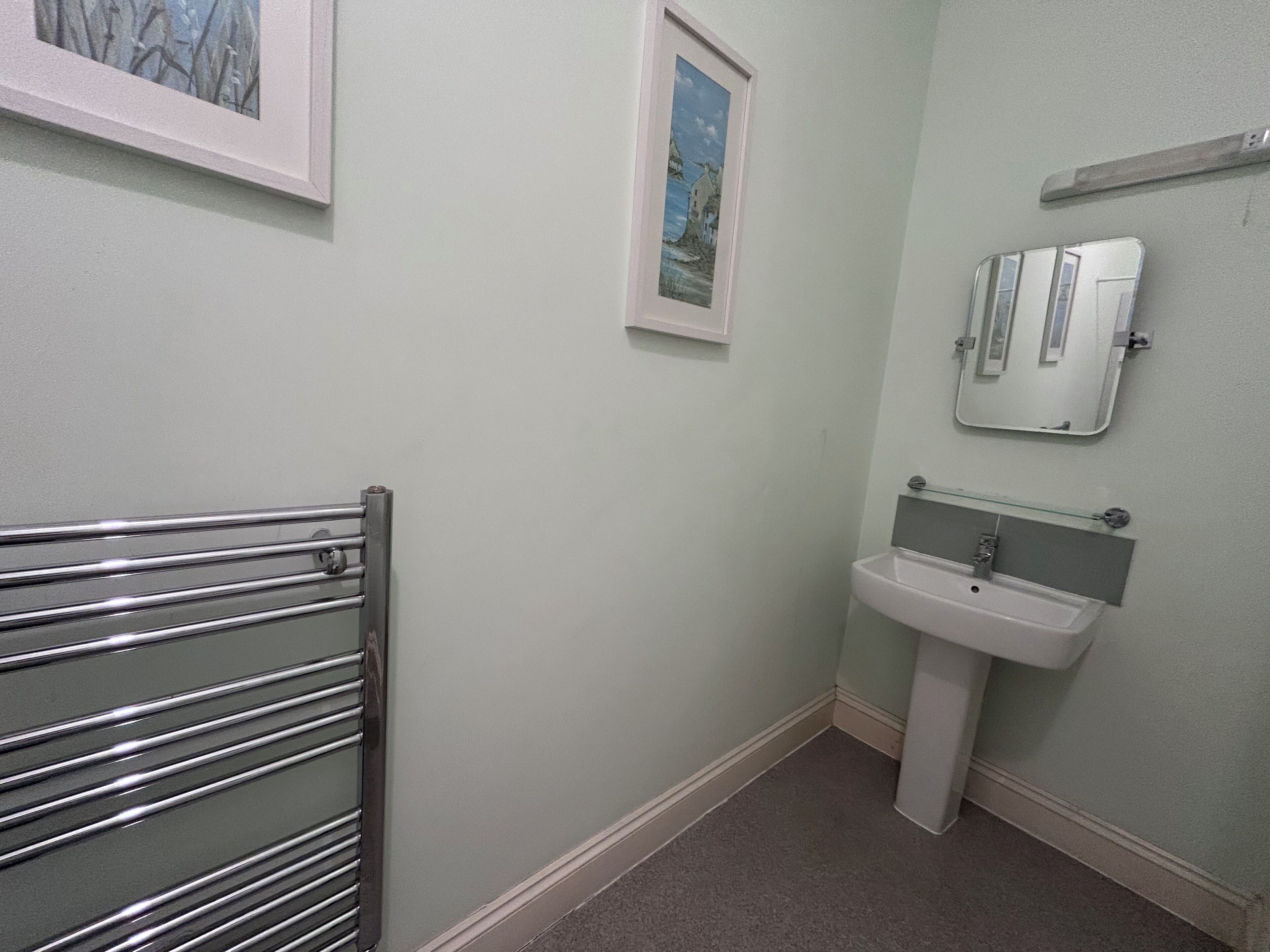 A bathroom with a towel rack, a sink, and two framed pictures on the wall.