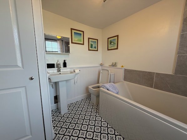 A bathroom with a white sink, toilet, and bathtub. There are three framed pictures on the wall. - Spring Garden Apartments (Gosport)