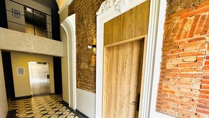 A hallway with a geometric patterned floor, a wooden door, and a brick wall. - Elegante loft urbano (Guadalajara)