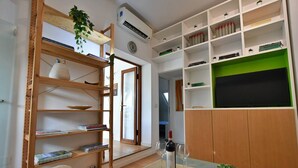 Habitació ben il·luminada amb una biblioteca de fusta, una paret d'accent verd, una pissarra i una petita planta en test.