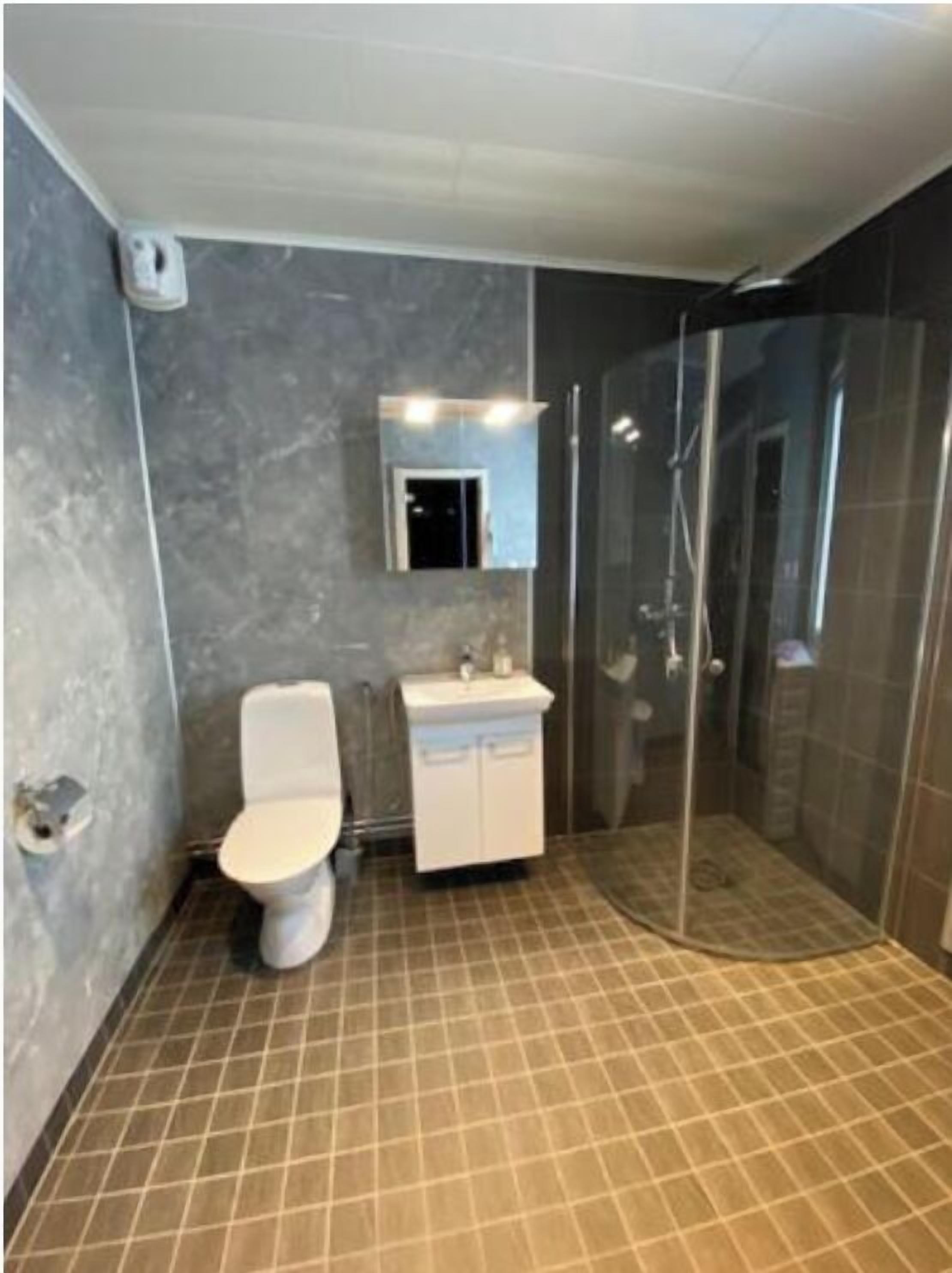 A bathroom with a toilet, sink, and glass shower enclosure.