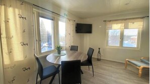 A conference room with a round table, black chairs, a potted plant, and a TV on the wall. - Stay In Karesuando (Karesuando)