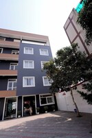 Un edificio de varios pisos con fachada moderna, múltiples ventanas y una entrada protegida por una reja.
