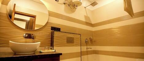 Un baño con un espejo redondo, un lavabo blanco, un inodoro y una zona de ducha.
