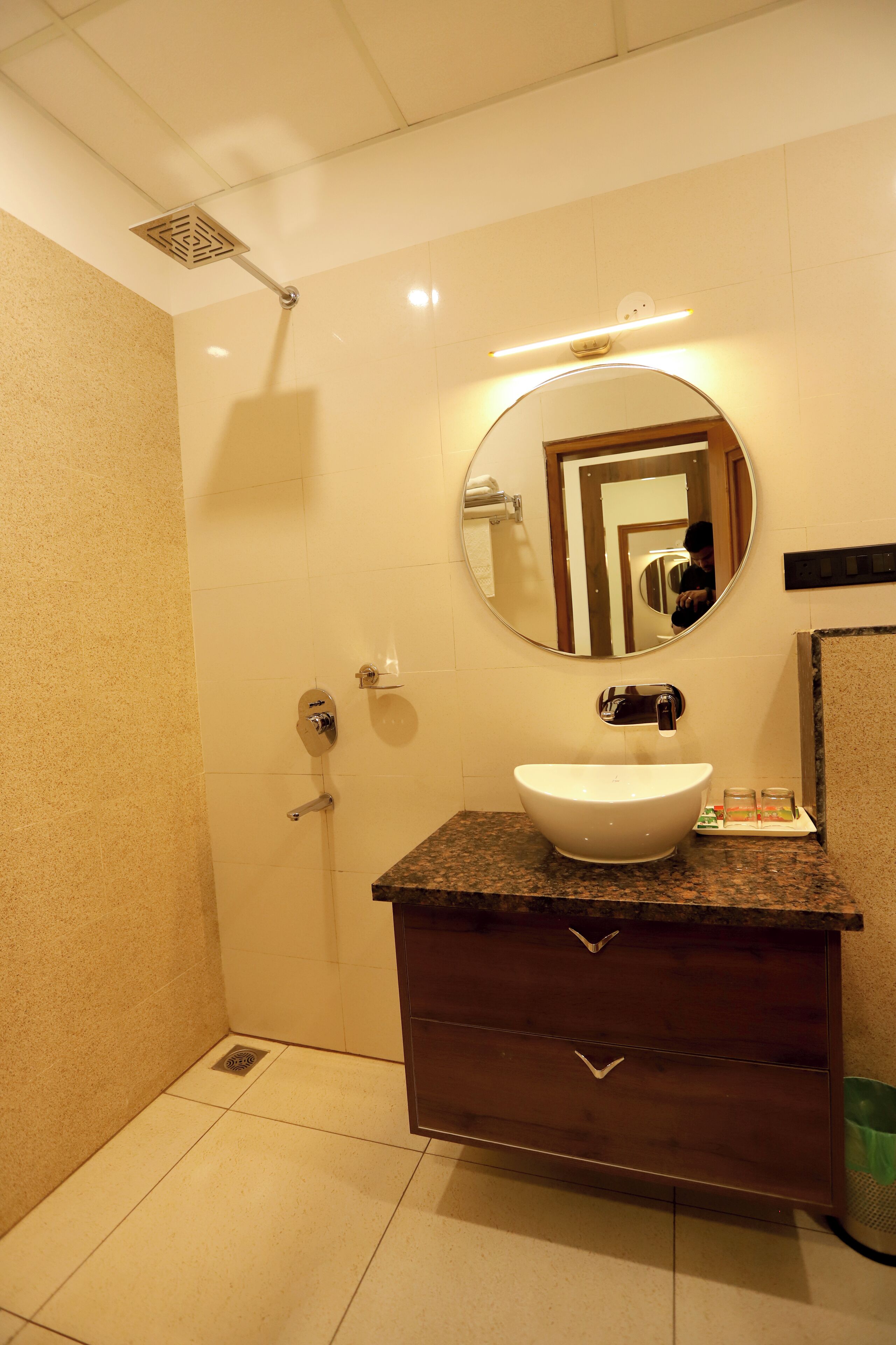 A bathroom with a sink, mirror, and shower.