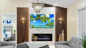 A modern living room with a flat-screen TV, a fireplace, and two grey sofas. - Grand Lux Villa /Heated Pool/Spa/Game fun/Nr Beach (Lantana)