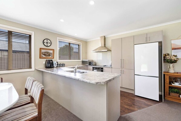 A modern kitchen with a central island, built-in appliances, and a dining area with striped chairs.