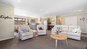 A spacious living room with two sofas, a coffee table, and a kitchen in the background. - Perfect Cromwell Family Getaway! (Cromwell)