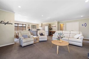 A living room with two sofas, a coffee table, and a dining area with a kitchen in the background.