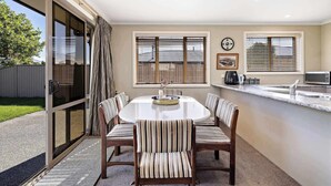 A dining area with a round table, six chairs, a kitchen counter, and a sliding glass door leading to a patio. - Perfect Cromwell Family Getaway! (Cromwell)