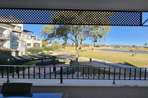 Ein Balkon mit Blick auf einen Golfplatz, einen Baum und ein Gebäude mit Balkonen.