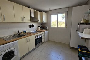 Cocina compacta con lavadora, horno y ventana que proporciona luz natural.