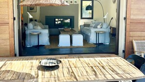 An open-plan living area with a large table, two sofas, and a hanging light fixture. - CASA LECCIA, Luxurious villa with swimming pool 5' drive from ST FLORENT (Patrimonio)