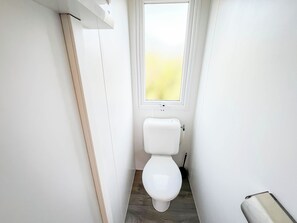 A narrow bathroom with a toilet, a window, and a radiator. - HappyCamp in Pioppeto Camping&Residence (Vasto)