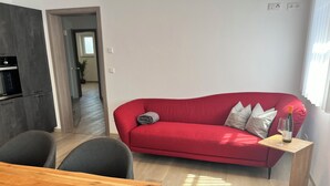 En moderne stue med en rød sofa, et træbord og et spiseområde.