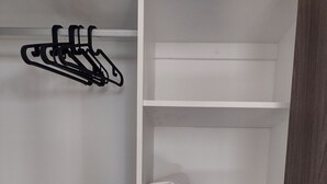 A wardrobe with multiple shelves, a hanging rack, and a door with a metallic handle. - Luxury Urban Apartment in Chapultepec (Guadalajara)