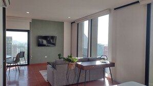 A modern living room with a sofa, a small table, and a TV mounted on the wall. - Luxury Urban Apartment in Chapultepec (Guadalajara)