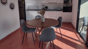 A compact kitchen with white cabinets, a round dining table with four chairs, and a small coffee station. - Luxury Urban Apartment in Chapultepec (Guadalajara)