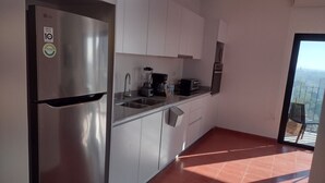 A modern kitchen with white cabinets, a stainless steel refrigerator, a coffee maker, and a toaster. - Luxury Urban Apartment in Chapultepec (Guadalajara)