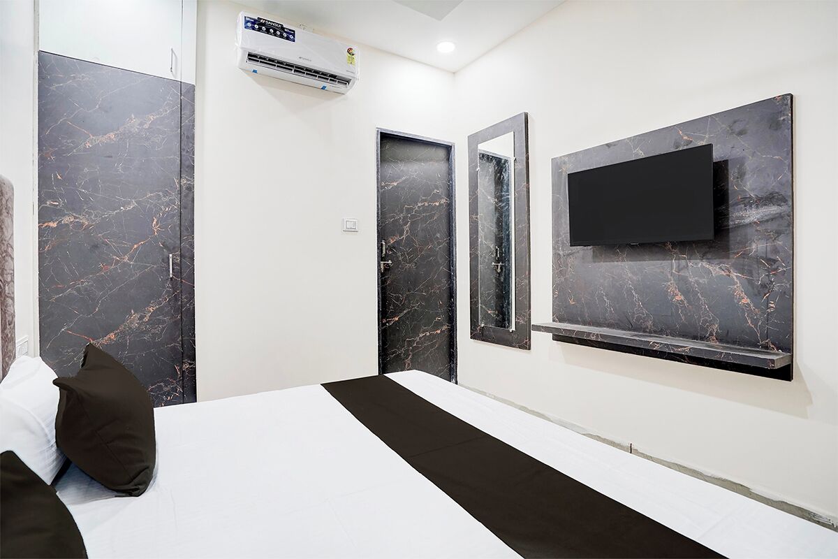 Une chambre d’hôtel moderne dotée d’un grand lit, d’un téléviseur à écran plat fixé au mur et de portes à motifs de marbre.