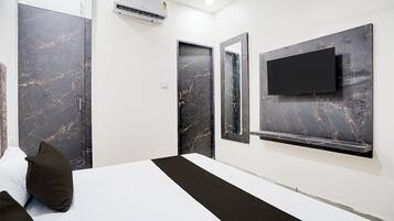 Une chambre d’hôtel moderne dotée d’un grand lit, d’un téléviseur à écran plat fixé au mur et de portes à motifs de marbre.