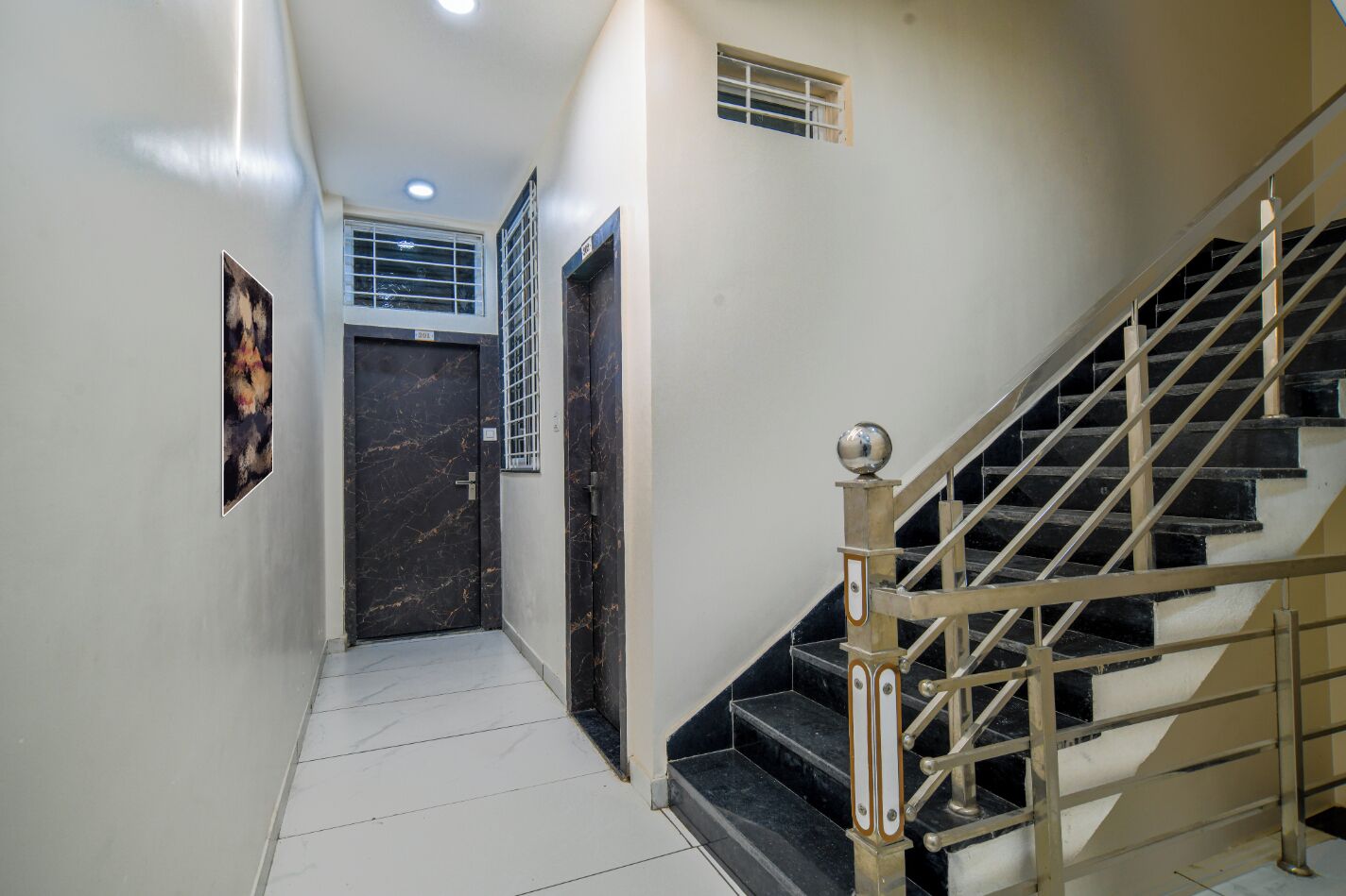 A hallway with a marble floor, a staircase with metal railings, and a door with a window.