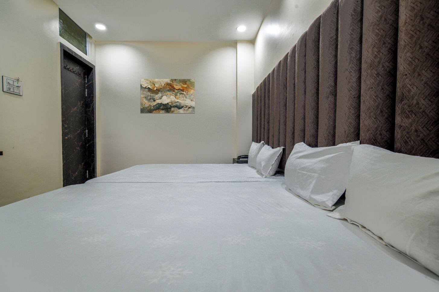 Ein Hotelzimmer mit einem großen Bett, einem Gemälde an der Wand und einer Tür mit Marmorverkleidung.