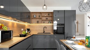 A modern kitchen with a built-in microwave, a sink, and a dining area with a table set for two. - Awesome home in Jursici (Jursici)