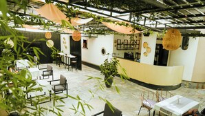A restaurant with tables and chairs, a counter, and hanging plants. - Kalih Villa (Kigali)